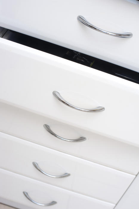 Row of white kitchen drawers with simple metal handles with one slightly open for storage of kitchenware