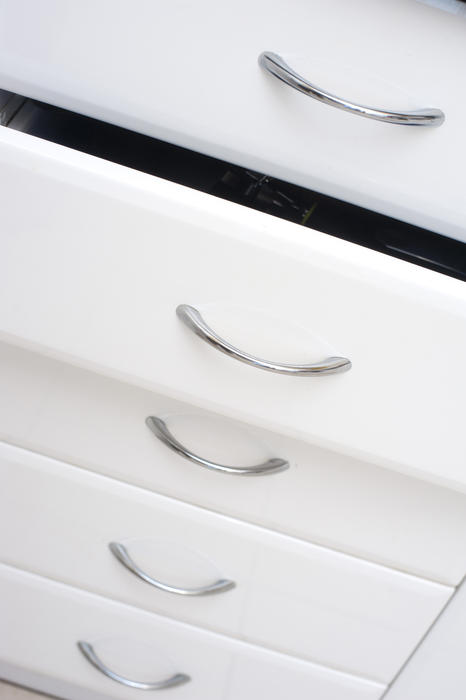 Row of white kitchen drawers with simple metal handles with one slightly open for storage of kitchenware