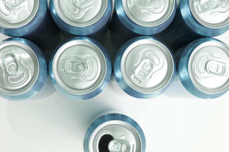 Drinks cans overhead view with two rows of sealed cans and a single opened can below