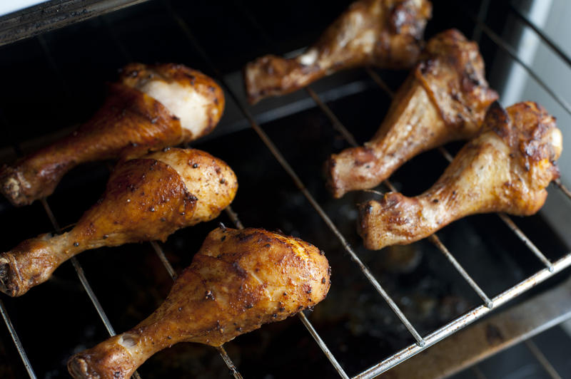 Close-up of six roasted chicken drumsticks on grill