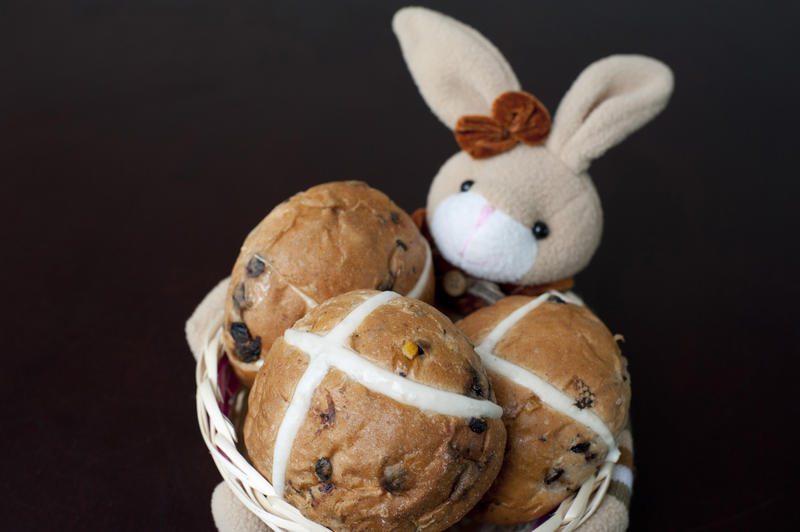 Cute little Easter bunny with traditional spicy fruity hot cross buns with a white cross commemorating the crucifixion of Christ