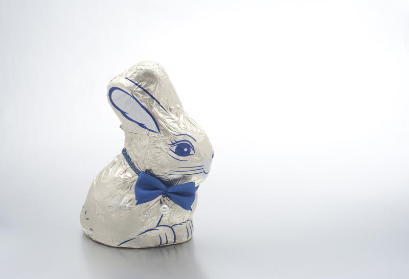 Cute Easter Bunny egg with bowtie wraped in decorative shiny foli on a studio background with copyspace