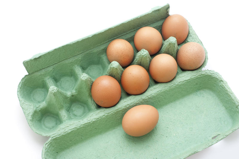Close up Fresh Brown Chicken Eggs in a Green Box Isolated on White Background