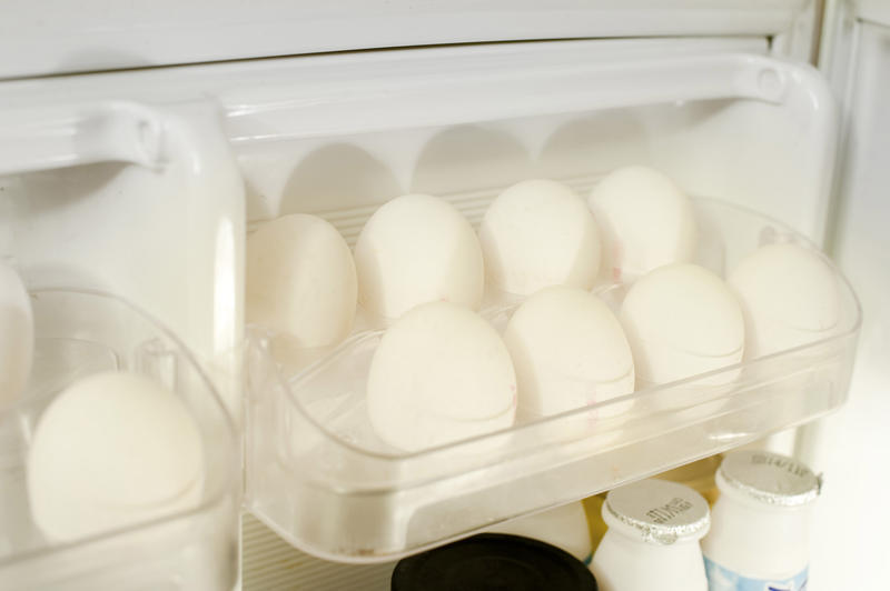 Tray of fresh white farm eggs in a refrigerator door kept cool for prolonged storage