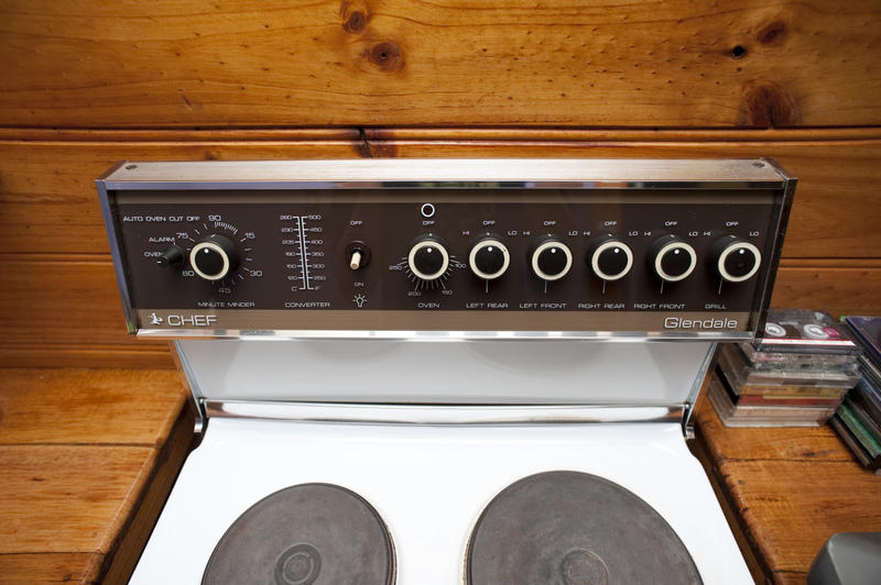 High angle view of two hotplates and the thermostat controls on a small domestic electric cooker in a rustic wooden kitchen