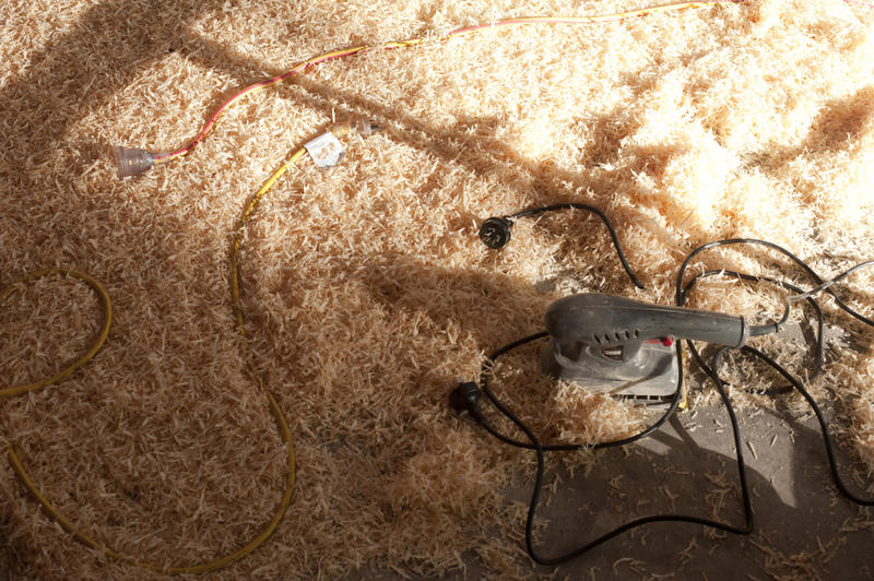 Electric sander with its cord lying in a bed of fresh wood shavings with copyspace in a DIY and renovation concept
