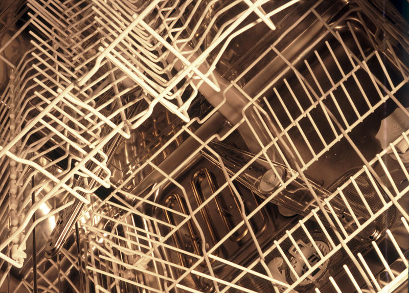 Closeup detail of the stainless steel interior of a domestic dishwasher showing the wire racks for stacking dishes and glassware