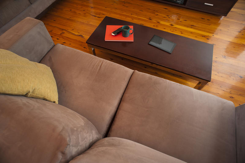 High angle view looking down on an empty lounge with a comfortable upholstered sofa and coffee table on a hardwood floor