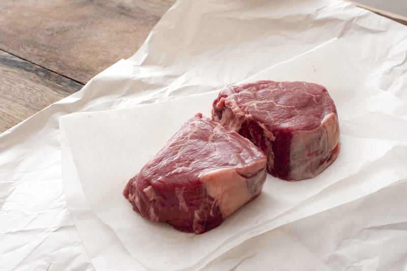 Two raw thick juicy tender eye fillet steak medallions on butchers paper waiting to be cooked for dinner