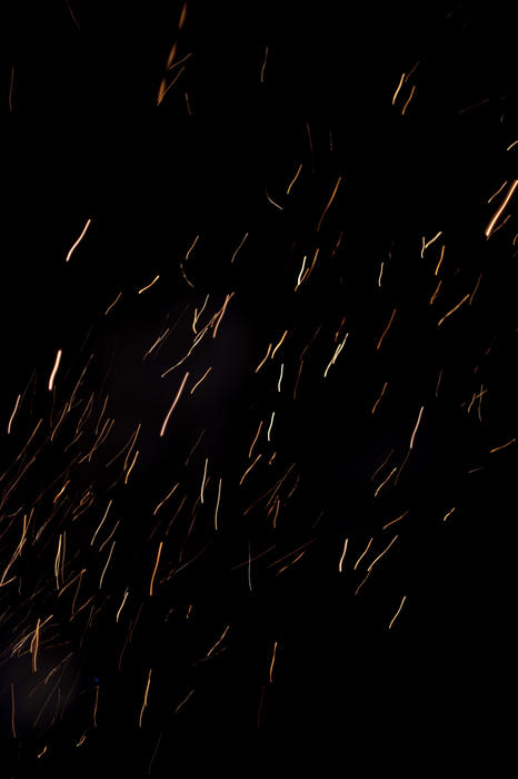 Falling sparks from a bonfire leaving light trails in the night sky