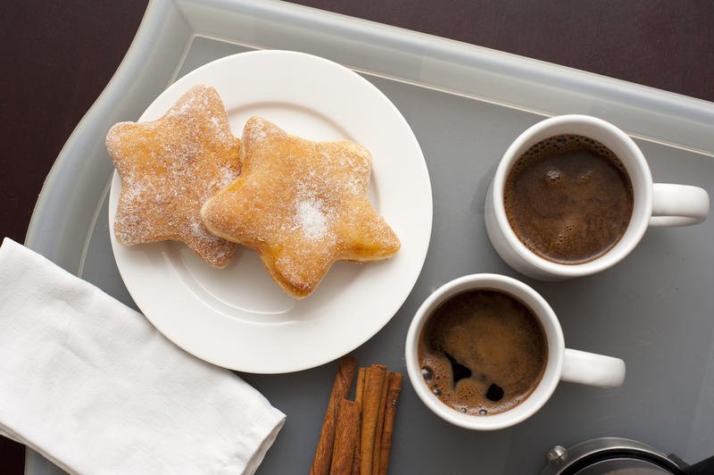 Festive coffee snack with two mugs of hot black espresso coffee with star shaped biscuits on a side plate on a tray, overhead view