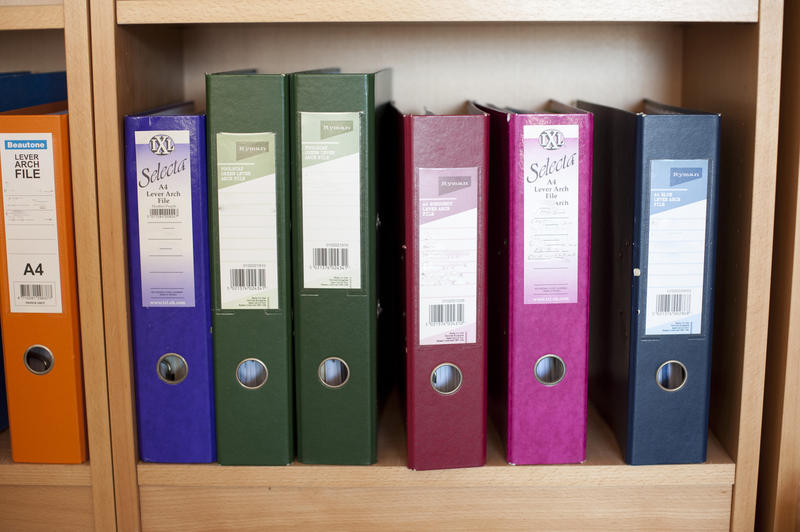 Close up Assorted Files on Colored Binders Placed Standing on Wooden Cabinet