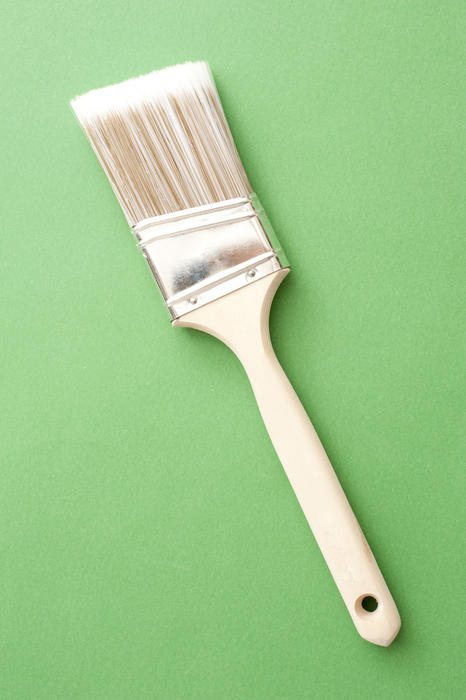 New finishing paintbrush with angled bristles for fine detailed interior work and edging lying diagonally on a green background with copyspace