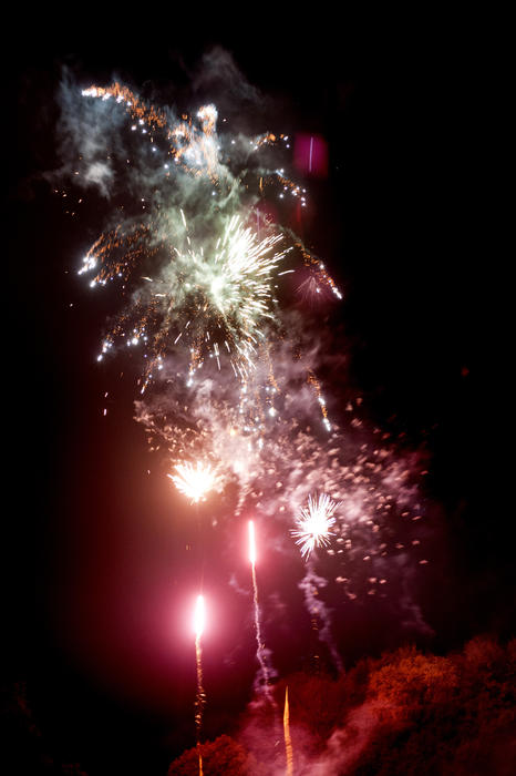 Red and white fireworks display lighting up the darkness with colorful bursts of glowing sparks during a Bonfire Night celebration