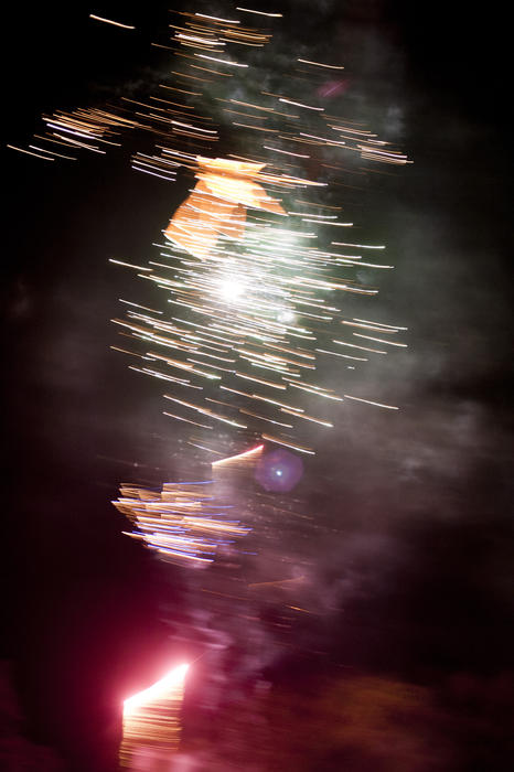 Firework blur with motion trails of colourful red and white fireworks bursting in a dark night sky for a colorful festive background