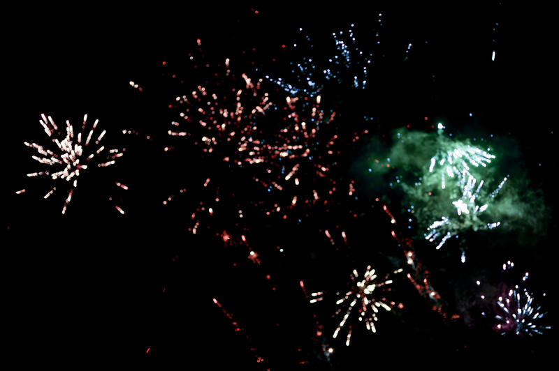 Colorful fireworks display with bursting rockets lighting up the night sky in a shower of fiery sparks celebrating a holiday or festival