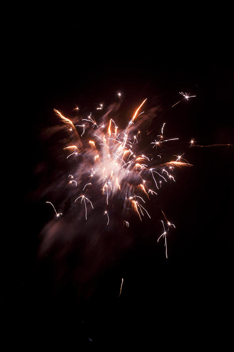 Colourful golden pink fireworks display bursting high in the night sky in an explosion of sparks during a festive or holiday celebration