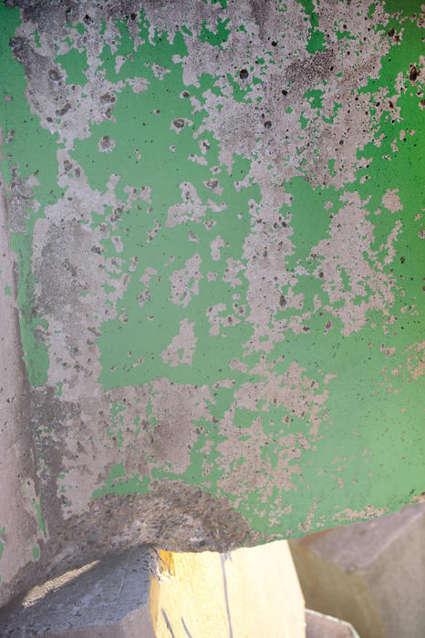 Architectural background texture of green flaking paint on a grunge grey cement wall