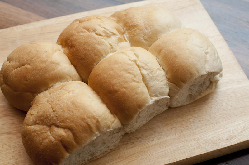 High angle view of a freshly baked batch of fresh round white cob rolls on a bread board
