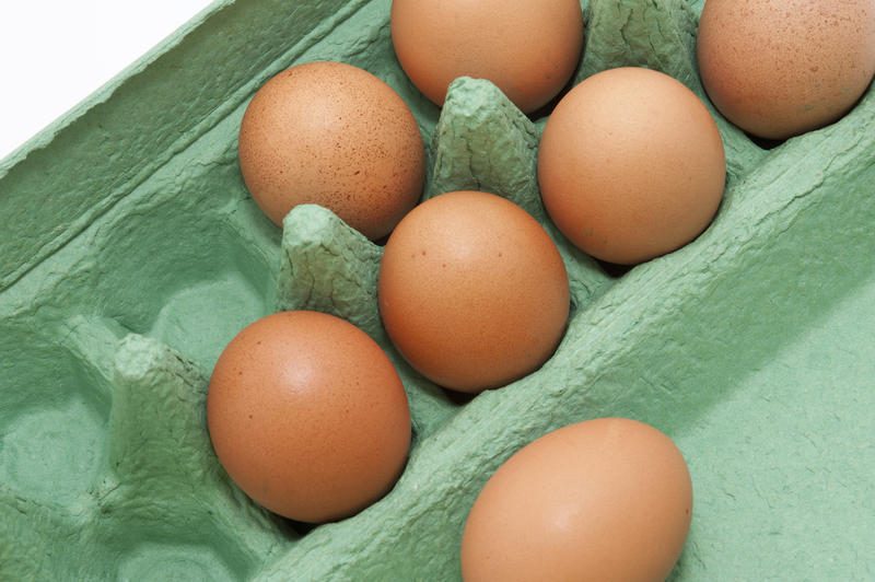 Close up Seven Fresh Brown Chicken Eggs on a Light Green Cardboard Tray