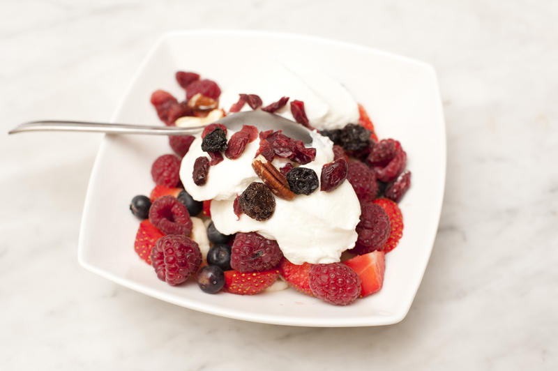 Fresh fruit and yoghurt for a tasty healthy breakfast with assorted rspberries, strawberries, blueberries, and raisins