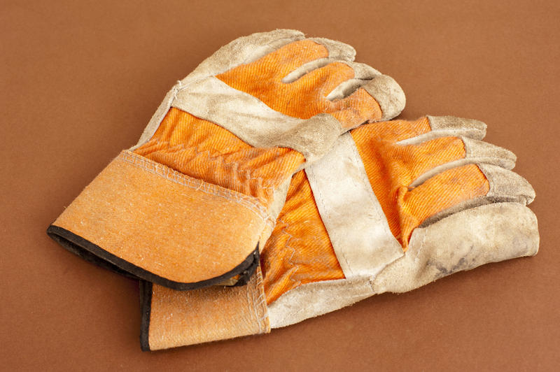 Close-up of a used pair of gardening protection gloves, on orange