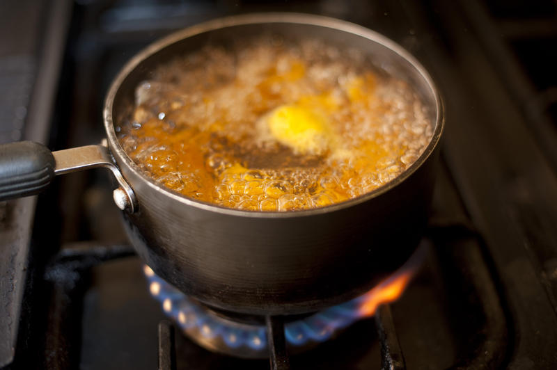 Fresh diced pumpkin boiling in a pot over a gas hob in the kitchen during cooking for the evening meal