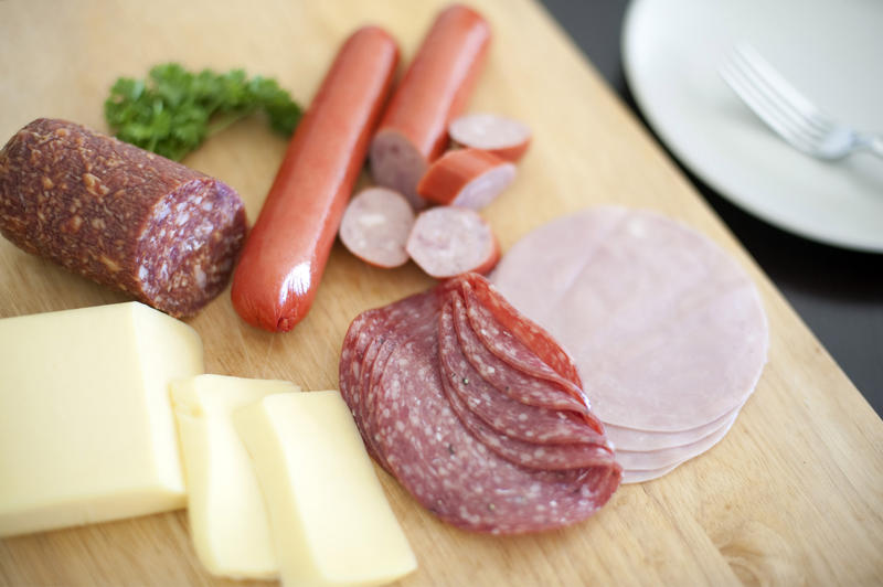 Nourishing German breakfast with sliced spicy salami or pepperoni sausage, cold ham and sliced cheese on a wooden chopping board