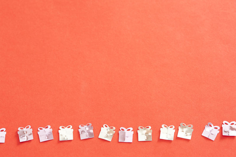 High Angle View of Silver Gift Confetti Arranged in a Line on Bright Orange Background with Ample Copy Space - Background Image for Birthdays or Anniversaries