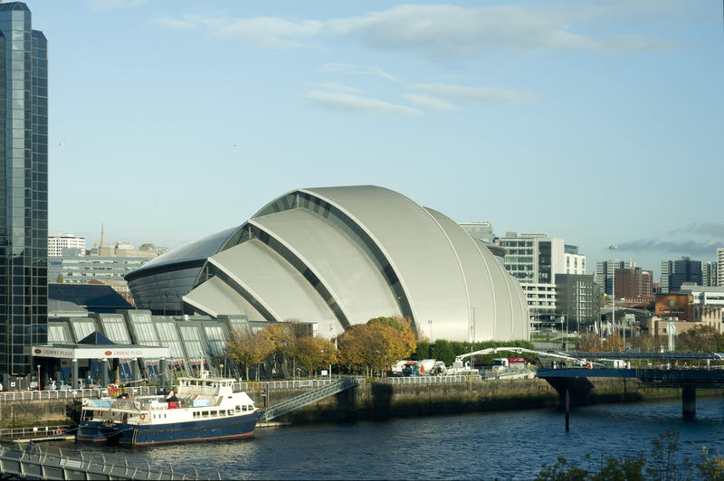 SECC, or the Scottish Exhibition and Conference Centre, on the banks of the River Clyde with boats moored at the wharf in Glasgow, Scotland