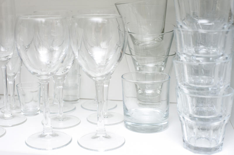 Stacked glassware on a kitchen shelf with an assortment of wineglasses and tumblers