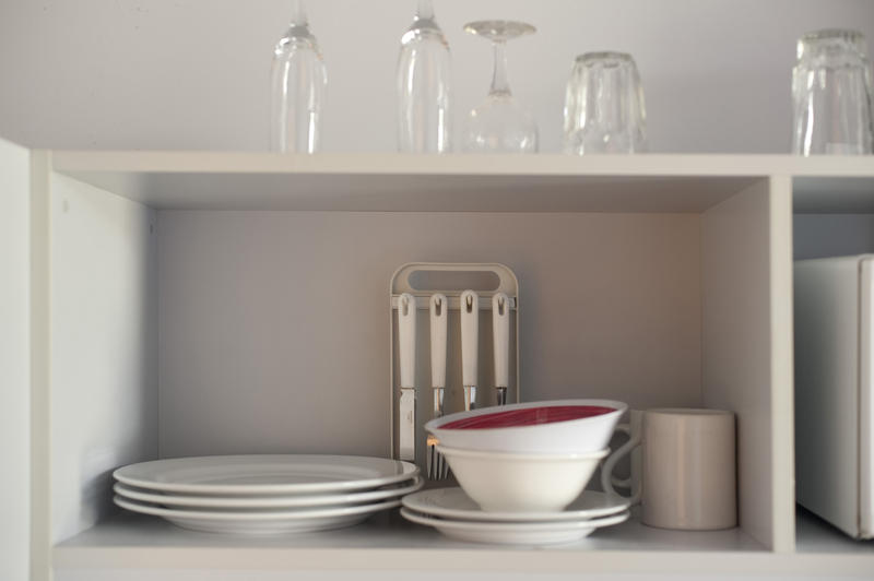 Open kitchen shelves used for storing clean crockery, glasses and cutlery hanging on a stand