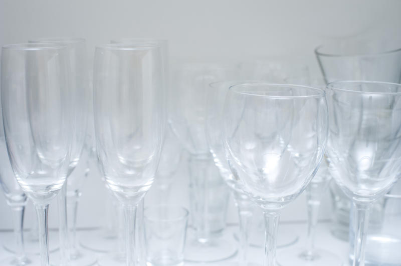 Assorted glasses including wineglasses, champagne flutes and tumblers stacked neatly on a kitchen shelf for storage
