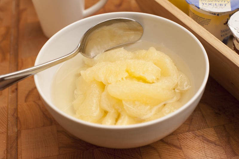 Yellow grapefruit segments in a bowl with a spoon served as breakfast or dessert