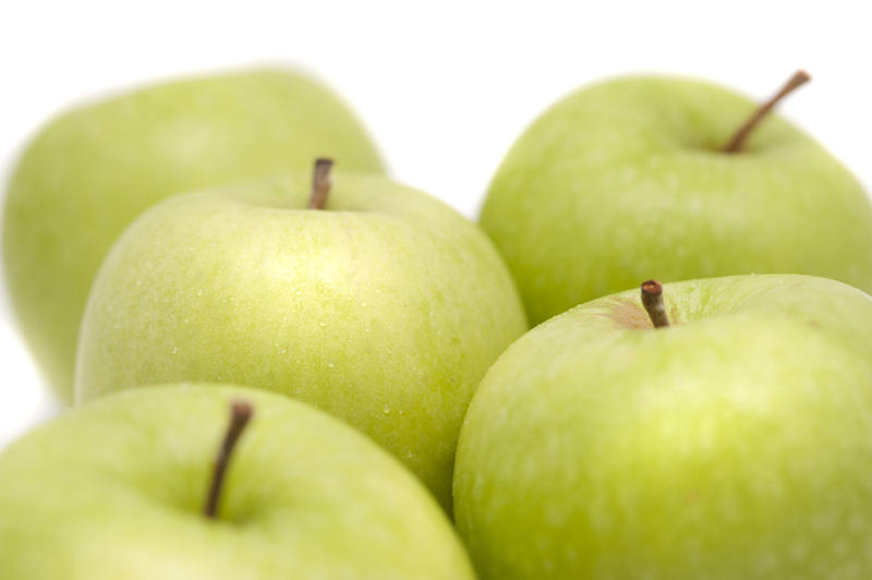 Close up of a group of crisp healthy fresh green apples over a white background