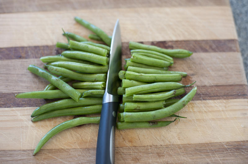 Close up Sliced Fresh Green String Beans on Top of a Wooden Cutting Board with Knife.