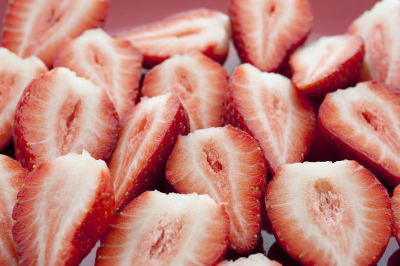 Halved strawberries carefully arranged to show the texture of the flesh during preparation of a delicious fruit dessert