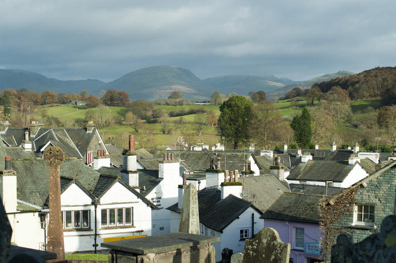 a view of the roof tops of the village of hawkshead across to the cumbrian hills in the distance including red screes and ill bell