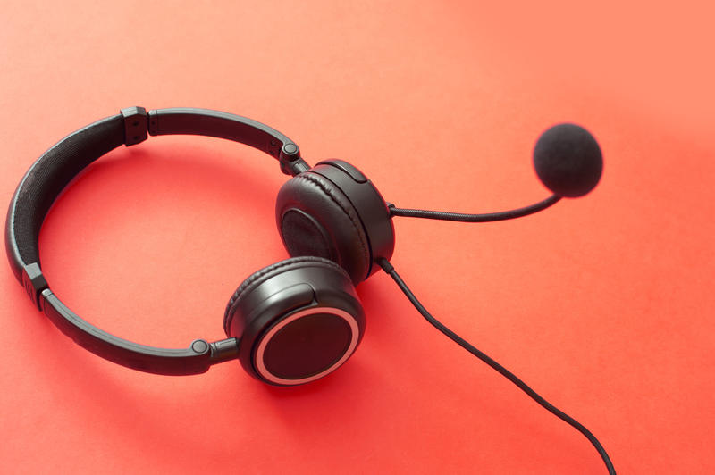 Headset lying on a red background conceptual of verbal communication, client services, assistance, telemarketing and a call center or help desk