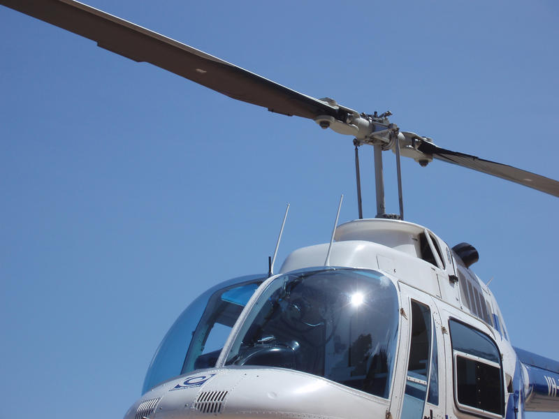 Close up of the windshield and cockpit and rotor blade on a helicopter against clear sunny blue sky