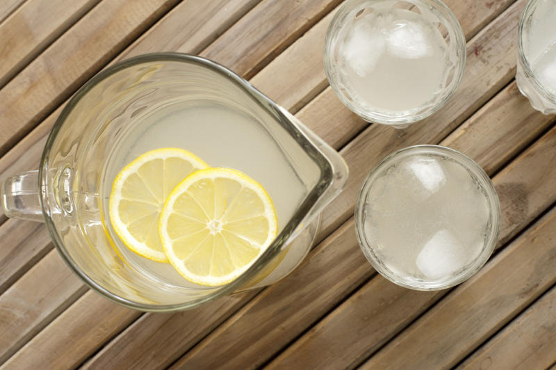 Homemade fresh healthy lemonade served in a jug and glasses on a slatted wooden picnic table for a refreshing summer dink, overhead view