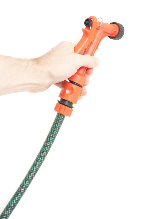 Close up Human Hand Holding a Hose with Orange Sprayer at the End. Isolated on White Background.