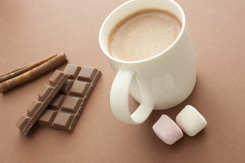 Hot chocolate drink with ingredients including marshmallows, stick cinnamon and a candy chocolate bar for a delicious winter beverage, high angle view