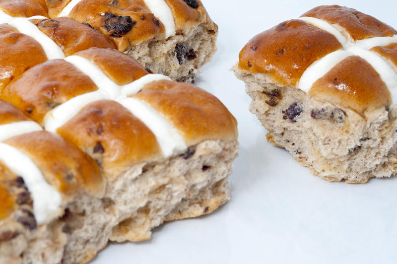 Freshly baked spicy Easter hot cross buns with glazed white pastry crosses on a white background