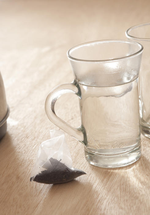 Close Up of Tea Bag on Wooden Table Next to Glass Mugs Filled with Hot Water - Getting Ready to Brew Tea