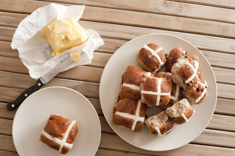 Many of baked buns with fondant on plates. Stick of butter and knife. From above