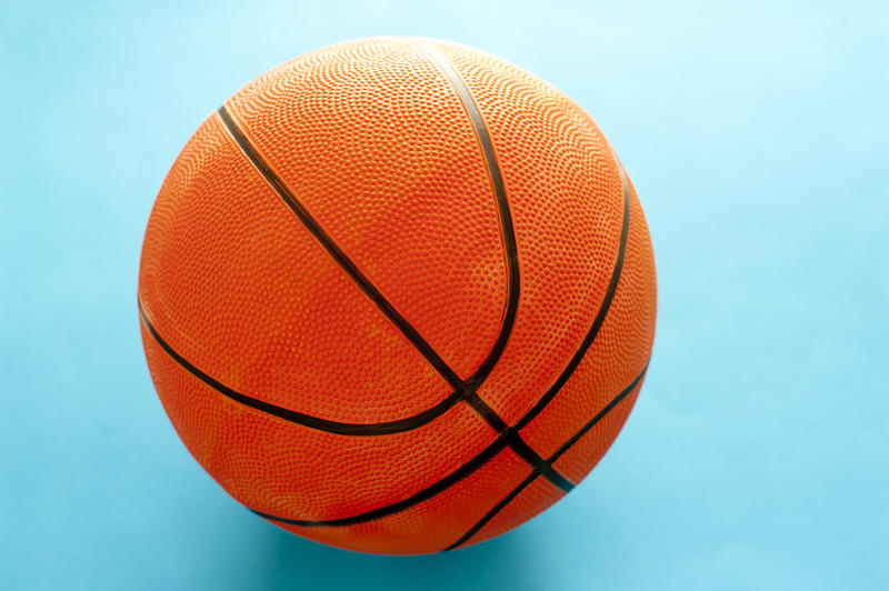 Close up of a single orange baseball on a colorful turquoise blue background with copyspace