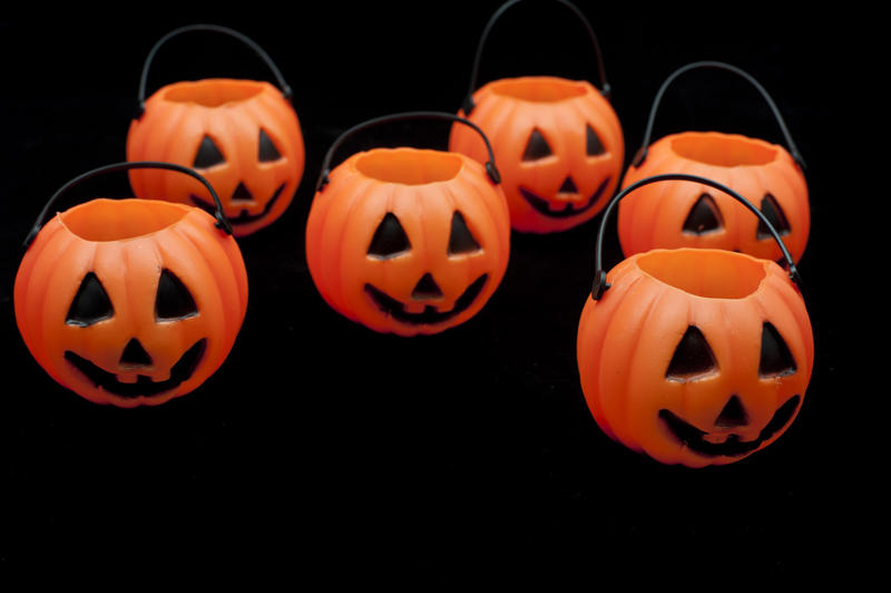 Group of orange Halloween jack-o-lantern decorations in the form of pumpkins with painted faces on a black background
