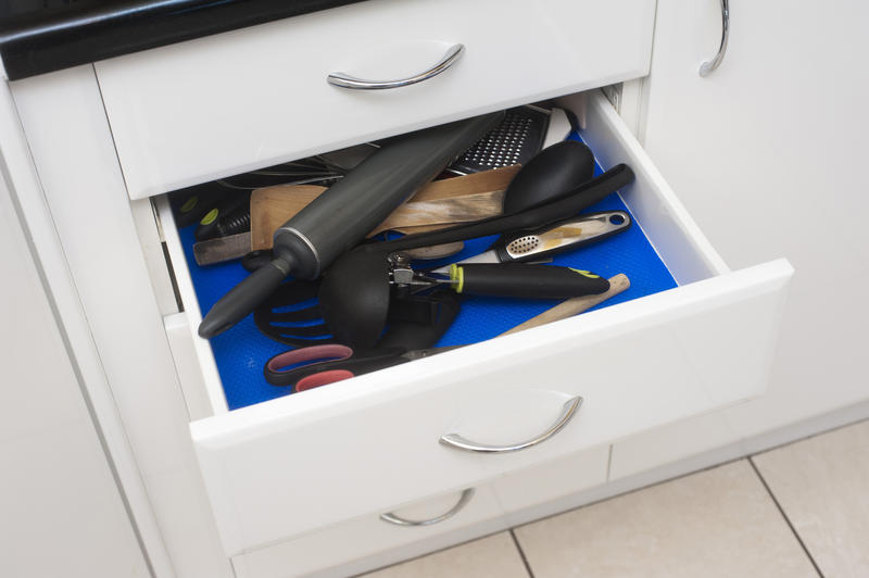 High angle view of an open kitchen drawer filled with a variety of cooking utensils and kitchenware in a jumbled pile