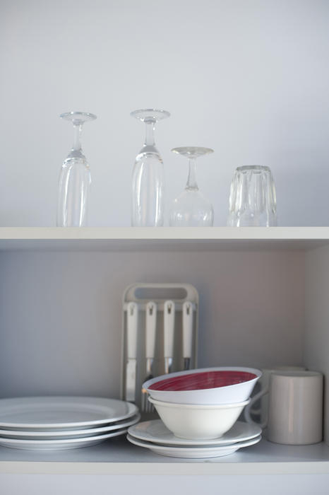 Open kitchen shelves stacked neatly with stored crockery, cutlery and glassware